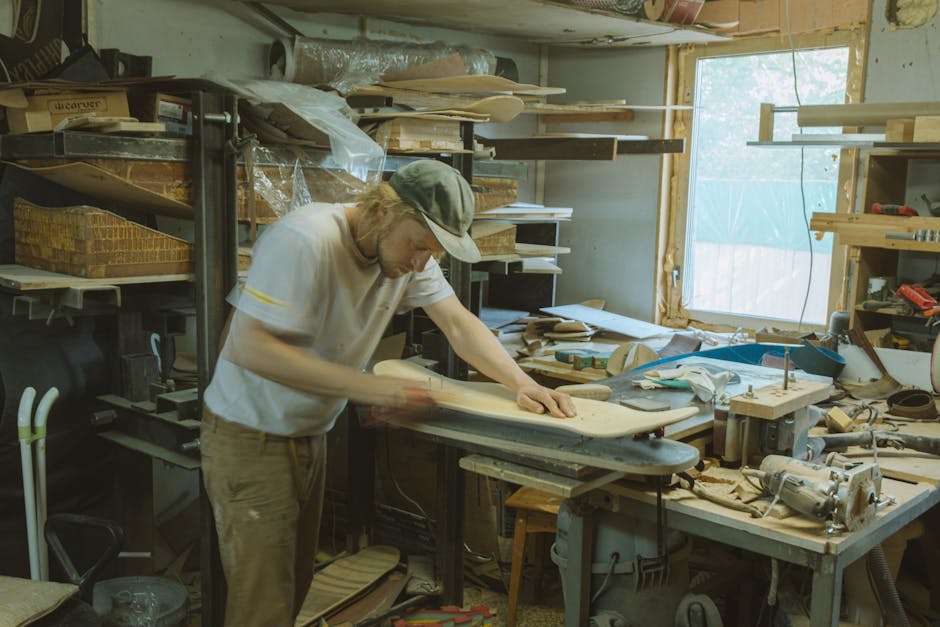 A man skillfully crafting a skateboard deck in a cluttered workshop, highlighting craftsmanship.
